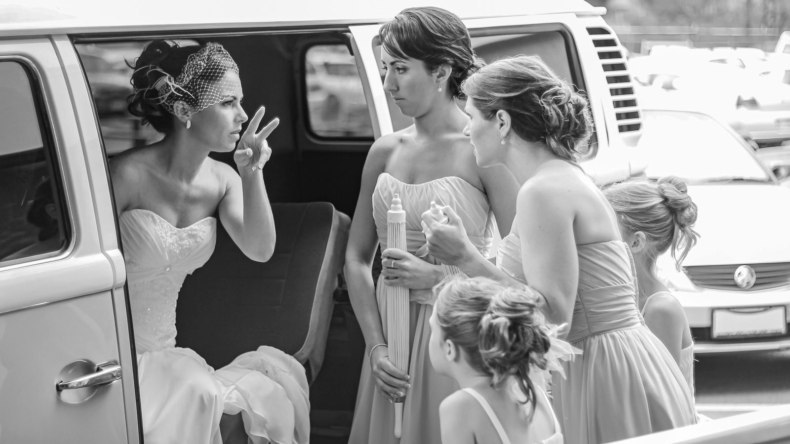 A bride in the doorway of a Kombi van talking with her bridesmaids and flower girls