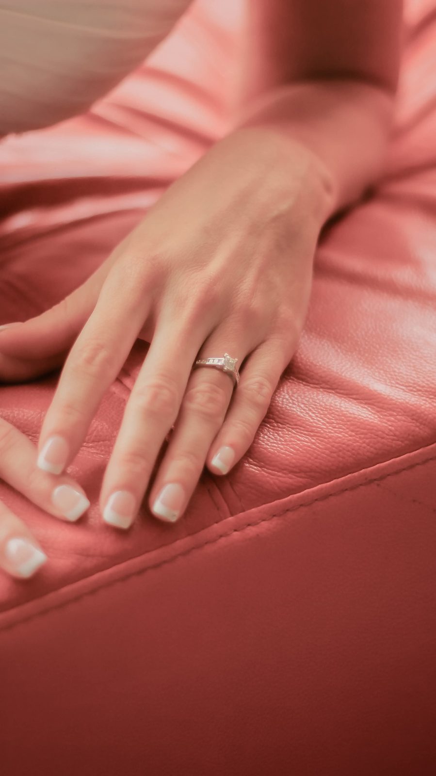 Detail of an engagement ring on the bride's hand resting on soft leather